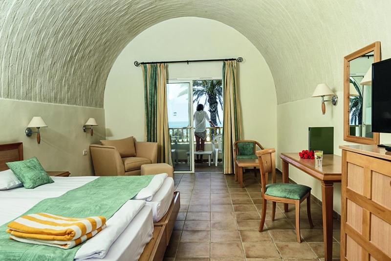納布勒的住宿－CALIMERA Delfino Beach Resort & Spa，酒店客房配有一张床、一张书桌和一台电视。