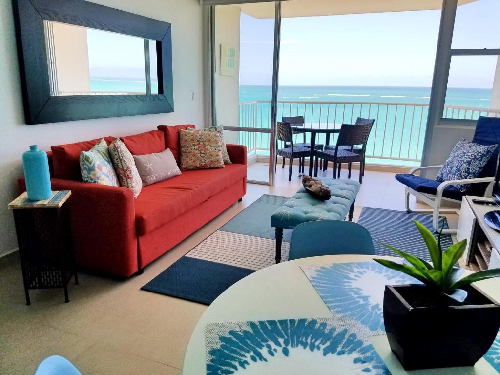 a living room with a red couch and a balcony at Marbella del Caribe 1608 in San Juan
