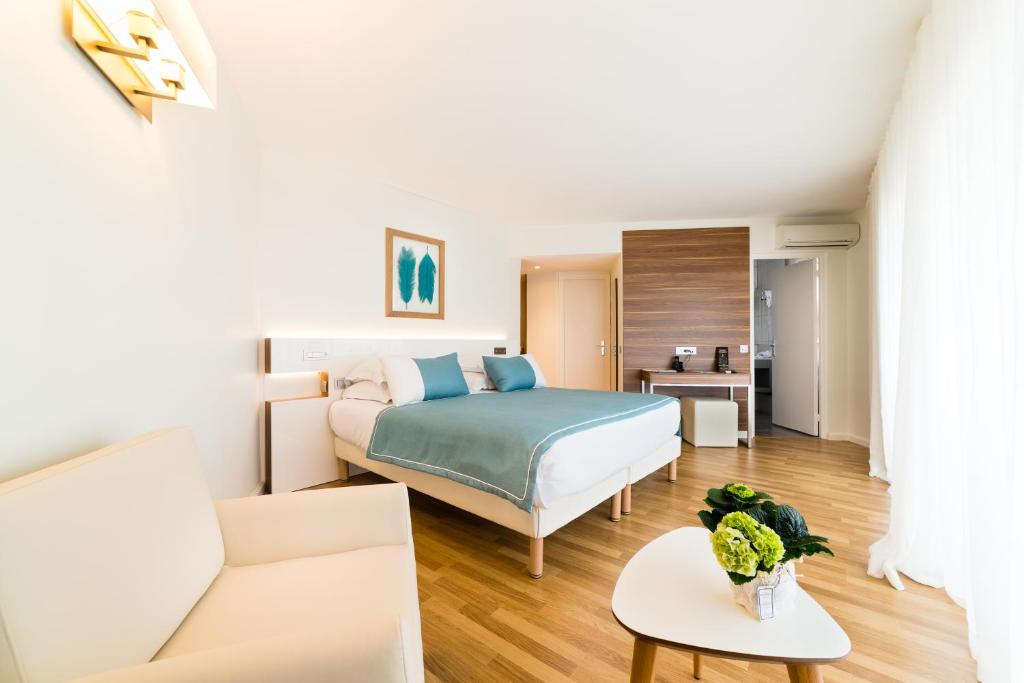 a bedroom with a bed and a living room at Hôtel Hélios in Juan-les-Pins