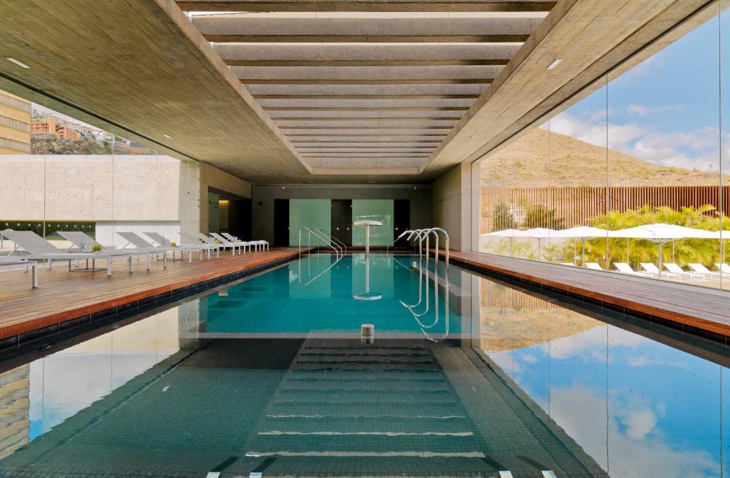 a swimming pool in a hotel with white chairs at Iberostar Heritage Grand Mencey in Santa Cruz de Tenerife