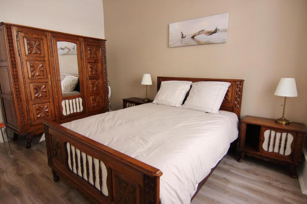 a bedroom with a large wooden bed with white sheets at Le Jules in Colmar