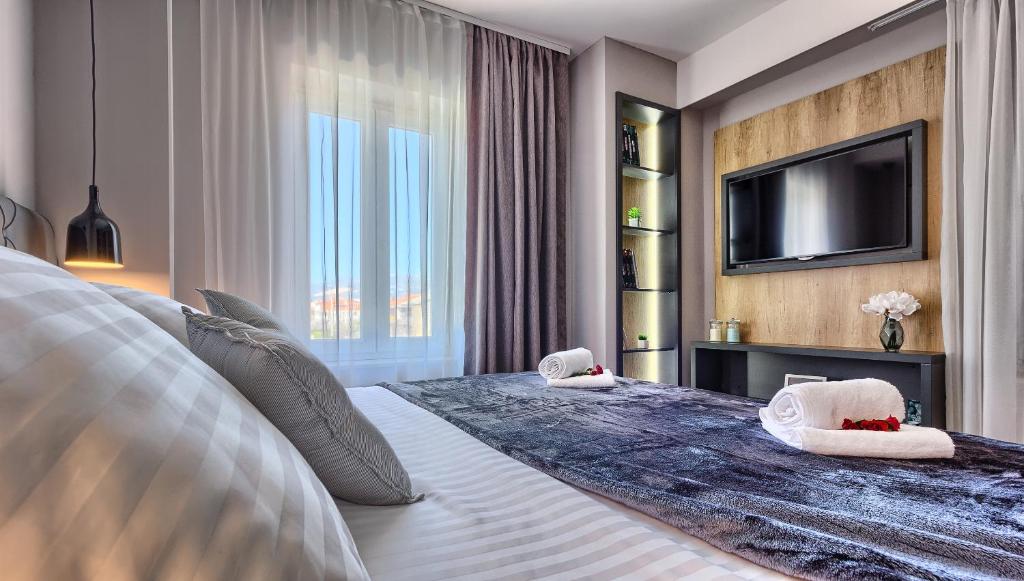 a bedroom with a large bed with a flat screen tv at Apartment Mondo Deluxe in Kaštela