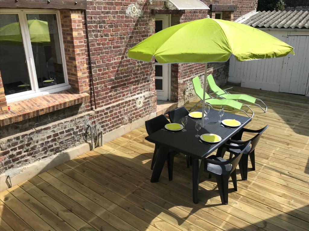 une table noire avec un parasol vert sur une terrasse dans l'établissement Maison de pêcheurs à Dieppe, à Dieppe