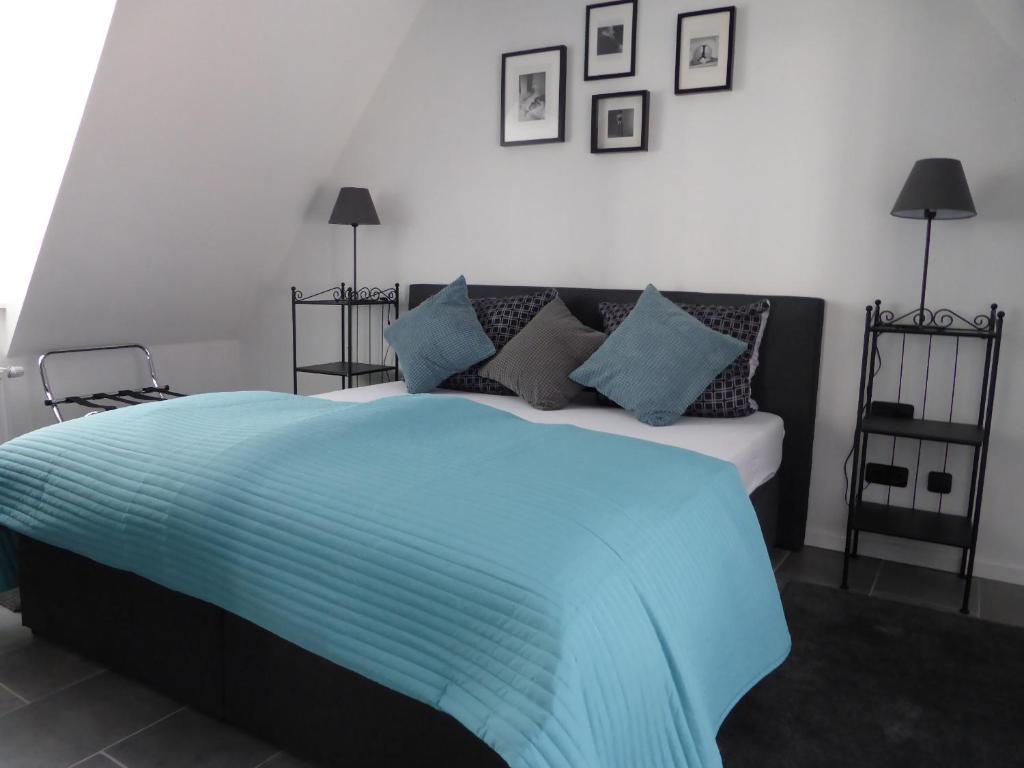Schlafzimmer mit einem Bett mit blauer Bettwäsche und Kissen in der Unterkunft CityStudiosTreysa in Schwalmstadt