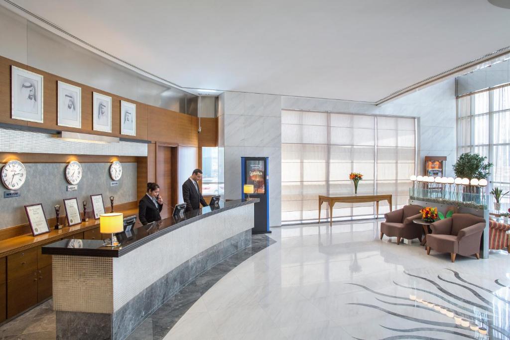 eine Lobby mit zwei Personen, die an der Rezeption stehen in der Unterkunft Nour Arjaan by Rotana-Fujairah in Fudschaira