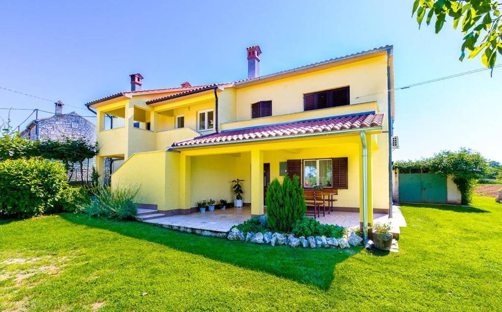 a large yellow house with a green yard at Holiday Home Grande in Grandići