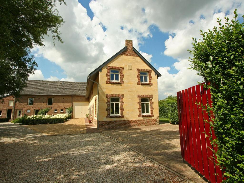 een stenen huis met een rood hek ervoor bij Restored farmhouse in Wijlre with two terraces in Wijlre