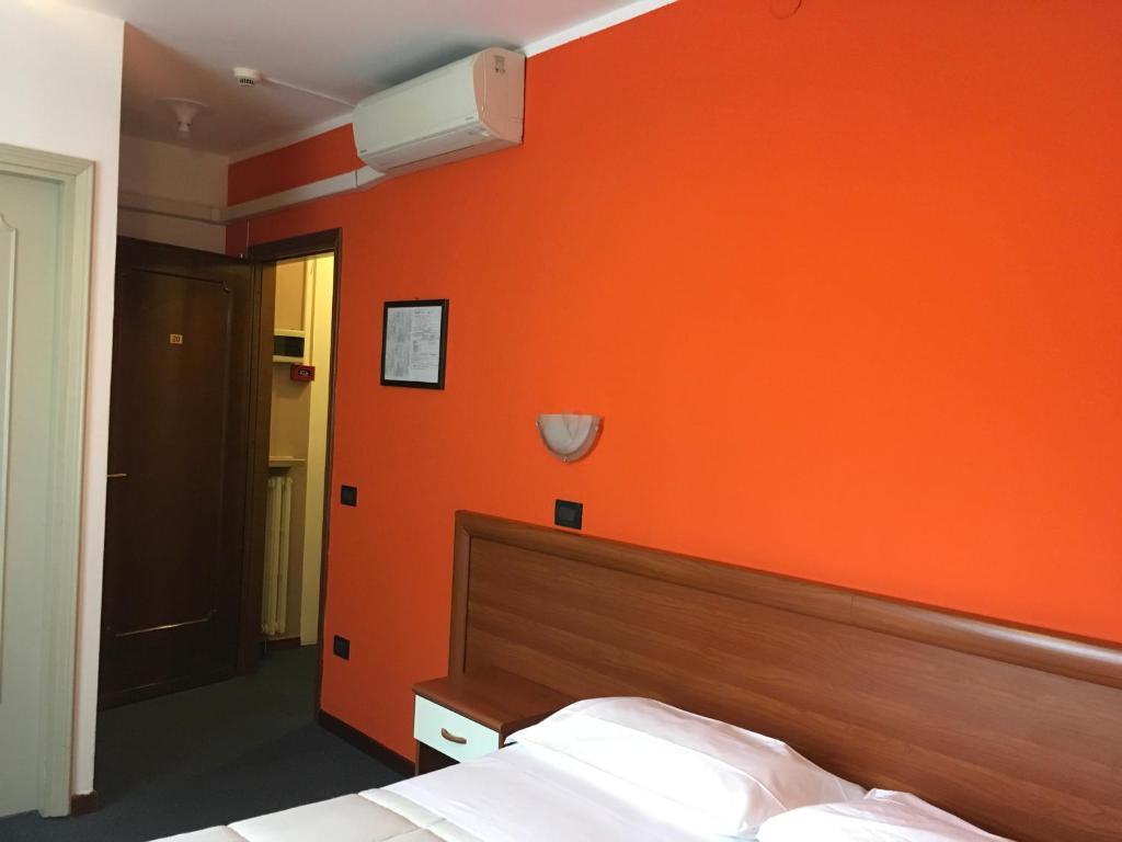 a bedroom with an orange wall and a bed at Hotel Cortina in Garda