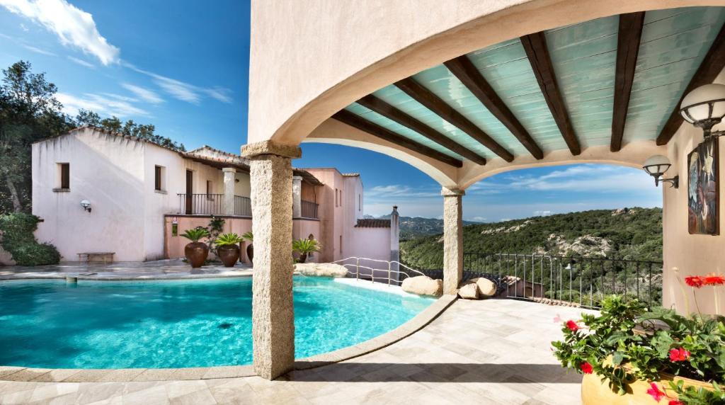 uma piscina exterior numa villa com um arco em Hotel Arathena em San Pantaleo