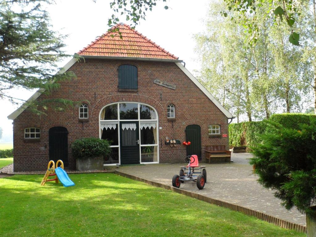 una casa de ladrillo con parque infantil en el patio en Detached farmhouse with play loft en Neede