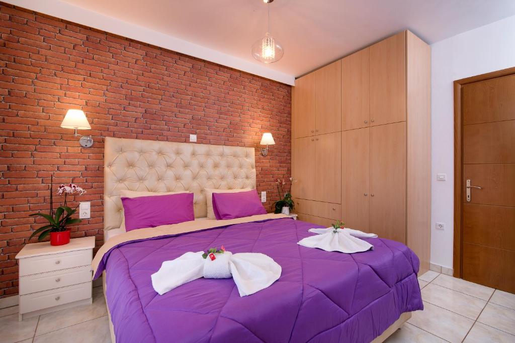 a purple bed in a room with a brick wall at Mouses Apartments in Limenas