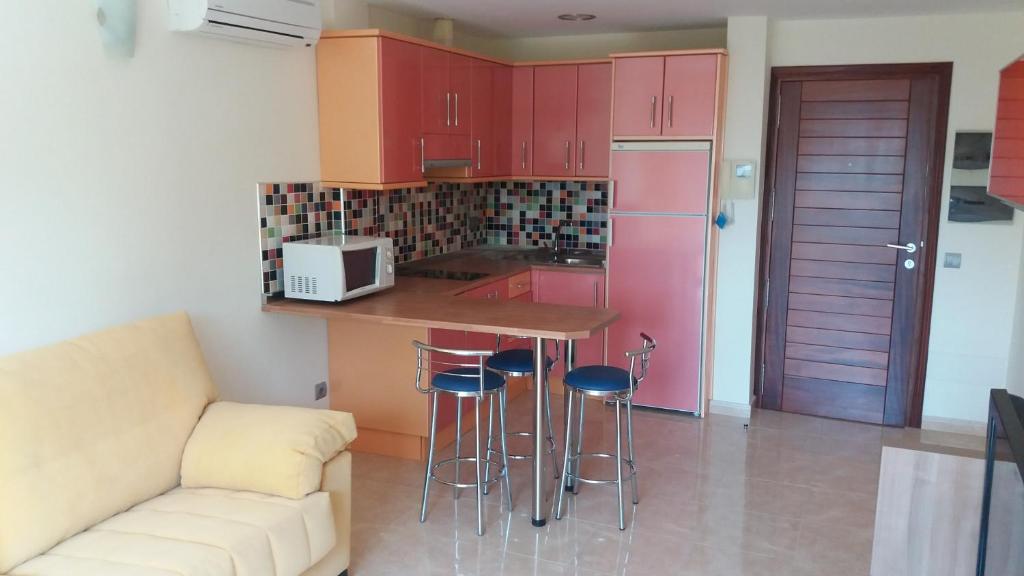 a kitchen with red cabinets and a counter with stools at Viva Cruce de Arinaga in Arinaga