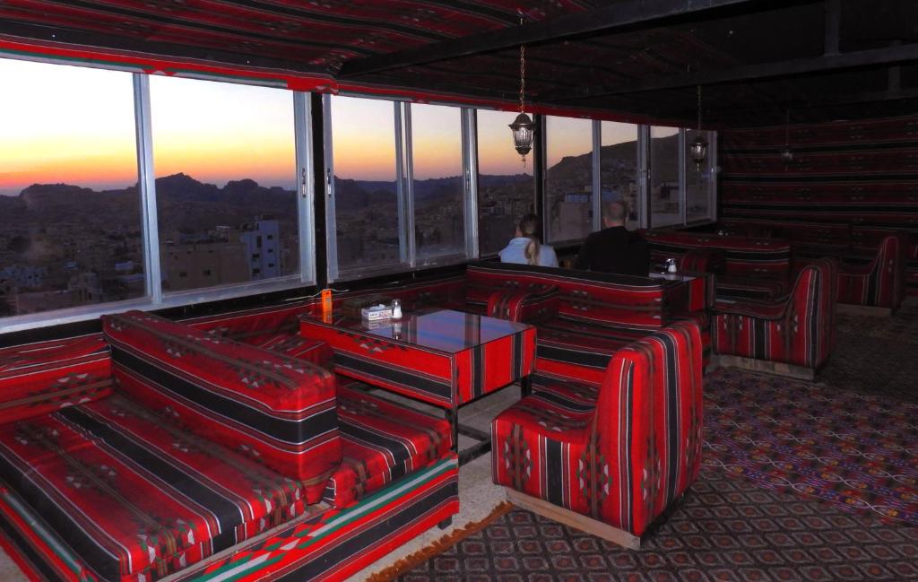 a restaurant with red chairs and a view of the city at Petra Gate Hotel in Wadi Musa