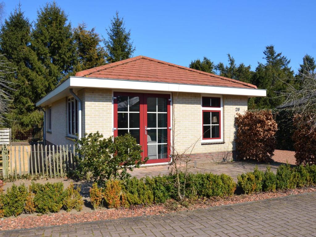 uma pequena casa com uma porta vermelha em Holiday home in the Veluwe in nature em Putten