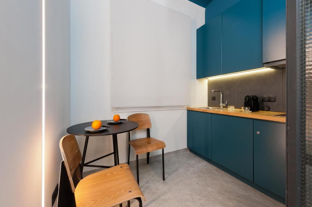 kuchnia z niebieskimi szafkami oraz stołem i krzesłami w obiekcie Syntagma Square Modern Apartments w Atenach