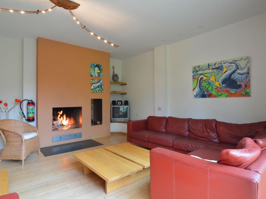 a living room with a red couch and a fireplace at Cosy apartment with terrace and pool in the garden in Waimes
