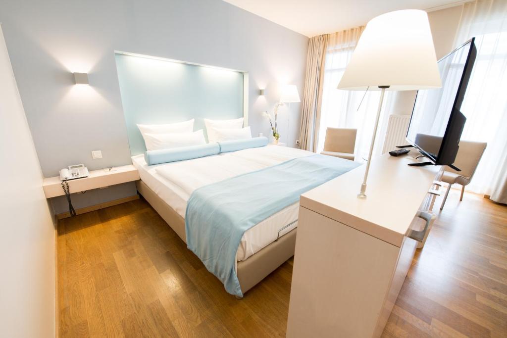 a hotel room with a bed and a television at Nymphe Strandhotel & Apartments in Binz