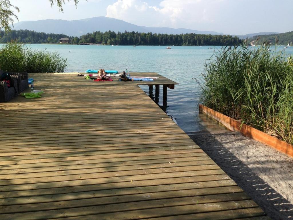 przystań nad jeziorem z ludźmi leżącymi na niej w obiekcie Ferienhaus Sonnhügel - Stissen w mieście Faak am See