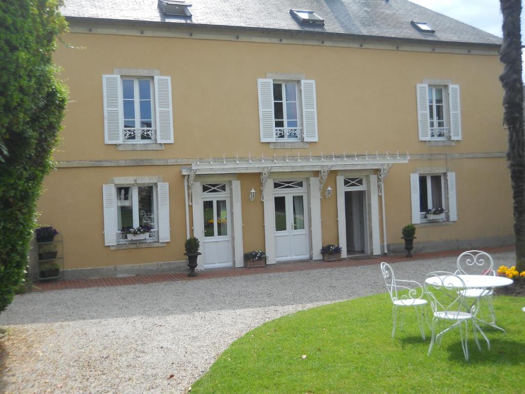 uma casa amarela com uma mesa e cadeiras no quintal em Chambres d'Hôtes La Gloriette em Ryes