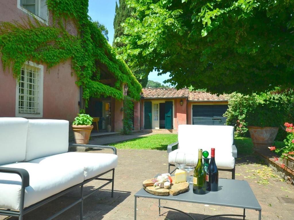 a patio with two chairs and a table with bottles of wine at Charming holiday home 4km from Lucca with a private pool in Lucca
