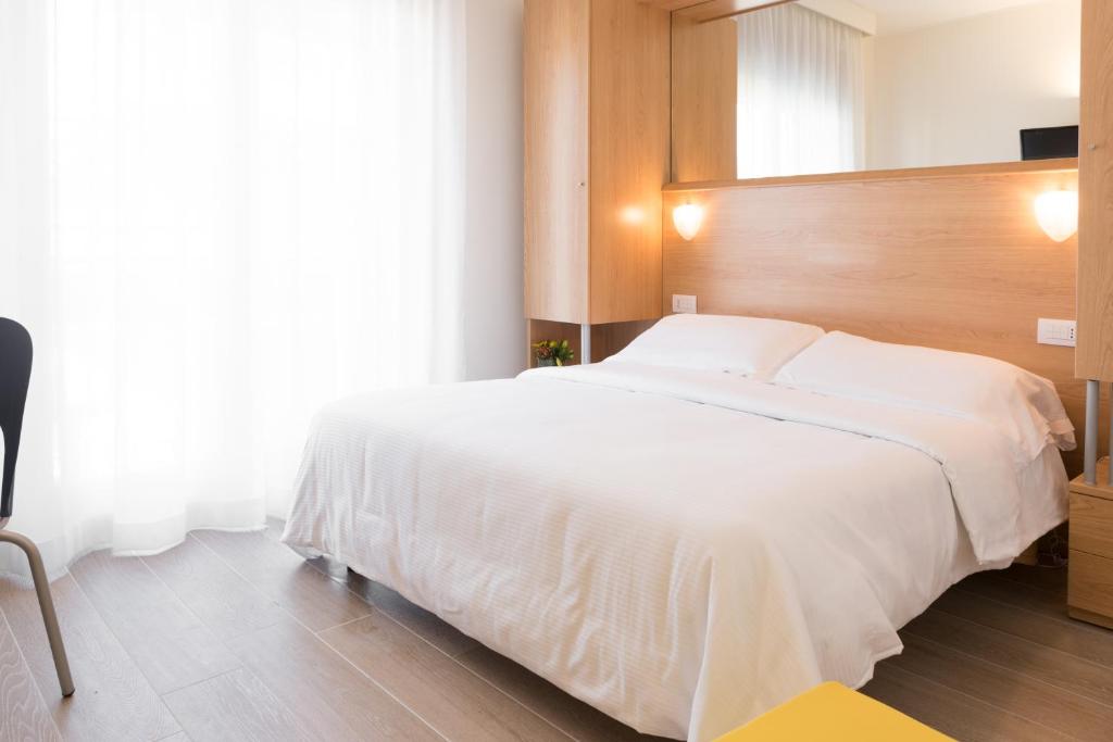 a bedroom with a large white bed with a wooden headboard at Hotel Mediterraneo in Sottomarina