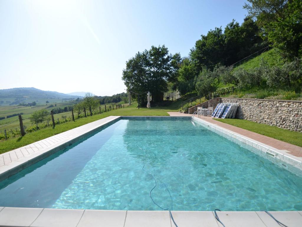 uma piscina com água azul e uma parede de pedra em Lovely Holiday Home with Pool in Monte Colombo em Monte Colombo