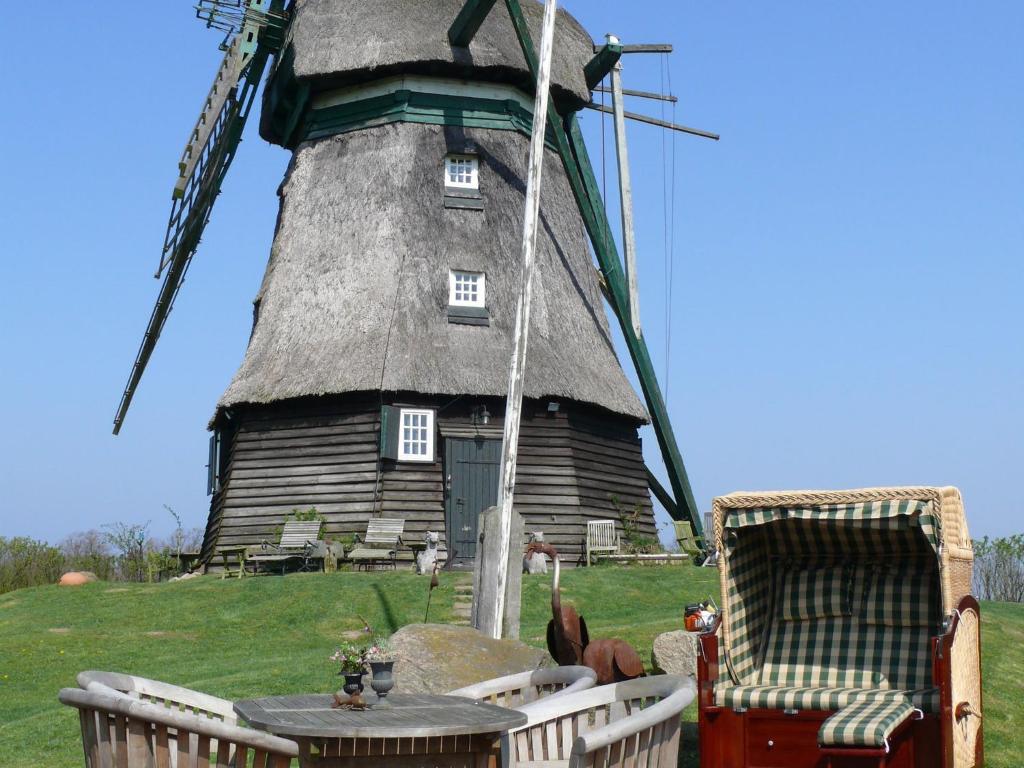 eine Windmühle mit zwei Stühlen und einem Tisch davor in der Unterkunft Beautiful authentic mill close to the beach in Wangels