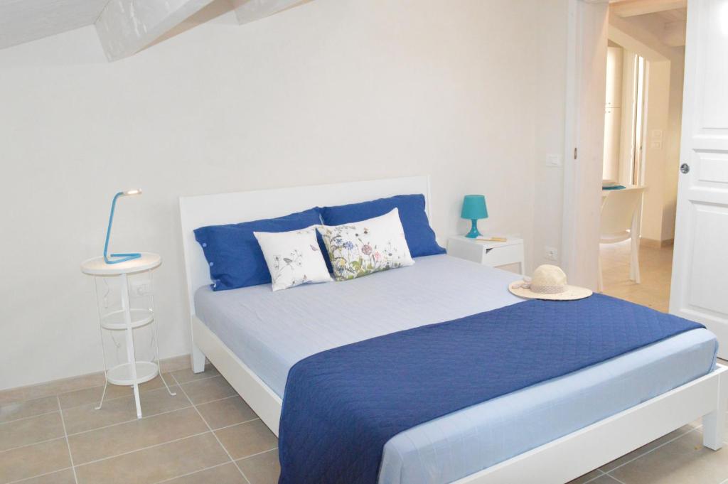 a white bedroom with a blue bed with a hat on it at Le Gemme in Castellammare del Golfo