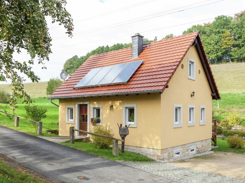 a small yellow house with a solar roof at Charming Holiday Home in Hohnstein ot Lohsdorf in Hohnstein
