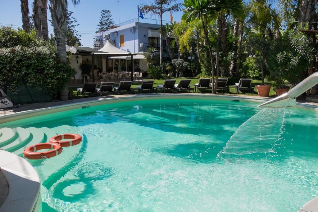 una grande piscina con due sedie rosse di Hotel Villamare a Fontane Bianche