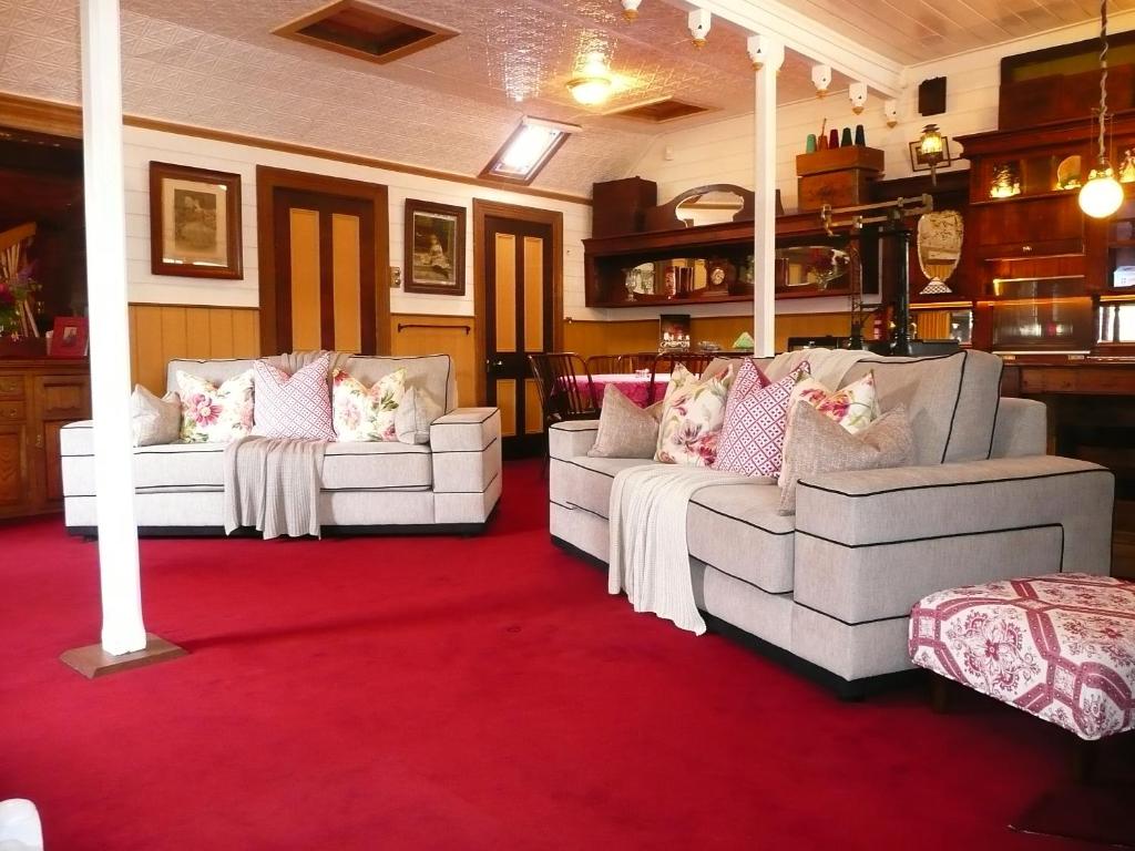 2 weiße Sofas im Wohnzimmer mit rotem Teppich in der Unterkunft Madam Saddler - On Fraser Clunes in Clunes