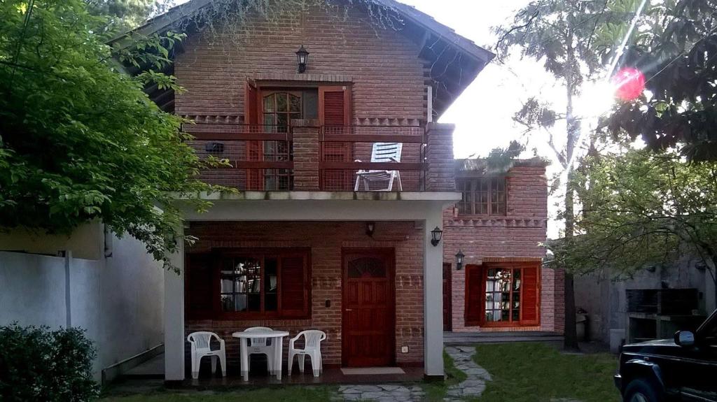 una casa de ladrillo con dos sillas blancas delante de ella en Cabañas El Maiten en San Clemente del Tuyú