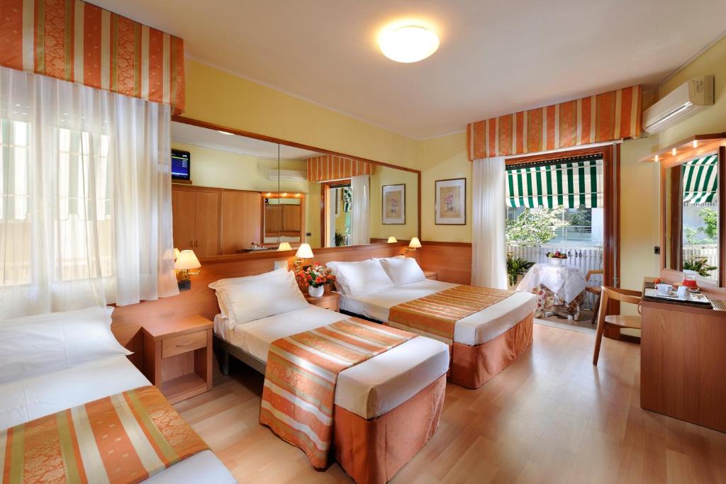 ein Wohnzimmer mit einem Bett und einem Sofa sowie ein Zimmer in der Unterkunft Hotel Al Prater in Lignano Sabbiadoro