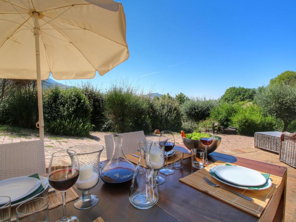 een houten tafel met wijnglazen en een paraplu bij Belvilla by OYO Ginestrilo in Assisi