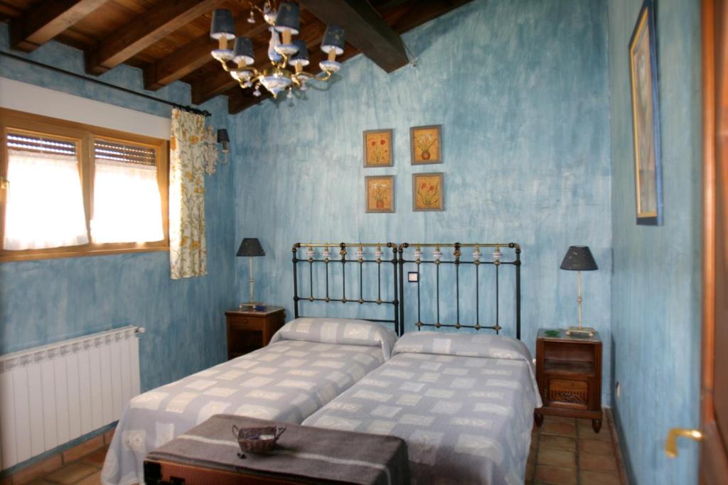1 dormitorio azul con 2 camas y mesa en Complejo Rural El Marañal, en Caspueñas