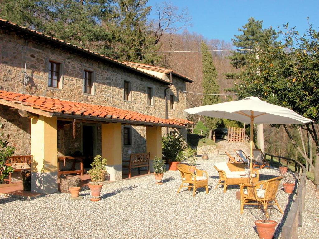 a patio with a table and an umbrella in front of a building at Beautiful Cottage in Pescia in San Quirico