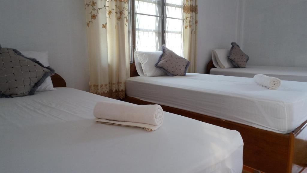 a room with two beds with white sheets and a window at Sanhak Guesthouse 1 in Ban Nahin-Nai (2)