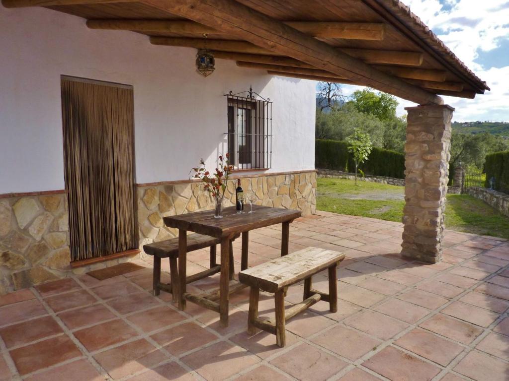 un patio avec une table et un banc ainsi qu'un bâtiment dans l'établissement Belvilla by OYO Hoyo del Lino, à Villanueva de la Concepción