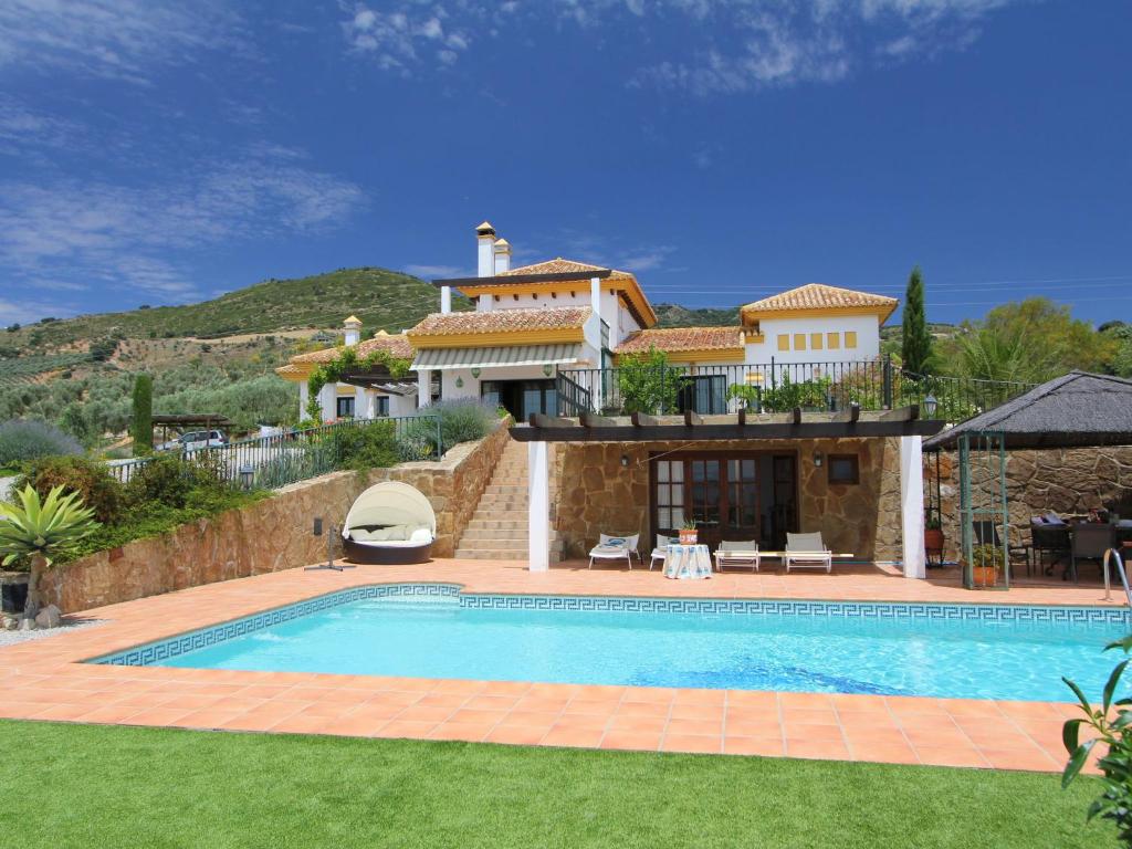 a villa with a swimming pool in front of a house at Belvilla by OYO Villa Los Chaparros in La Joya