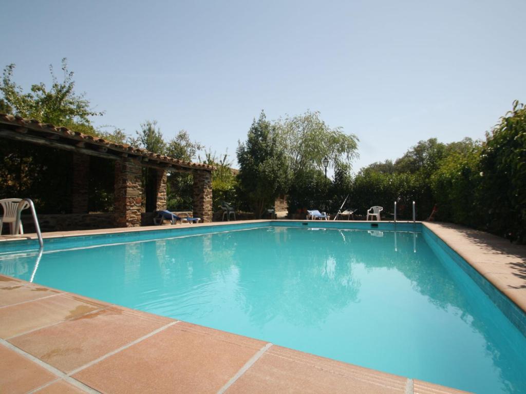 a large blue swimming pool with two chairs in it at Rural Farmhouse in Valencia de Alc ntara with Pool in La Borrega