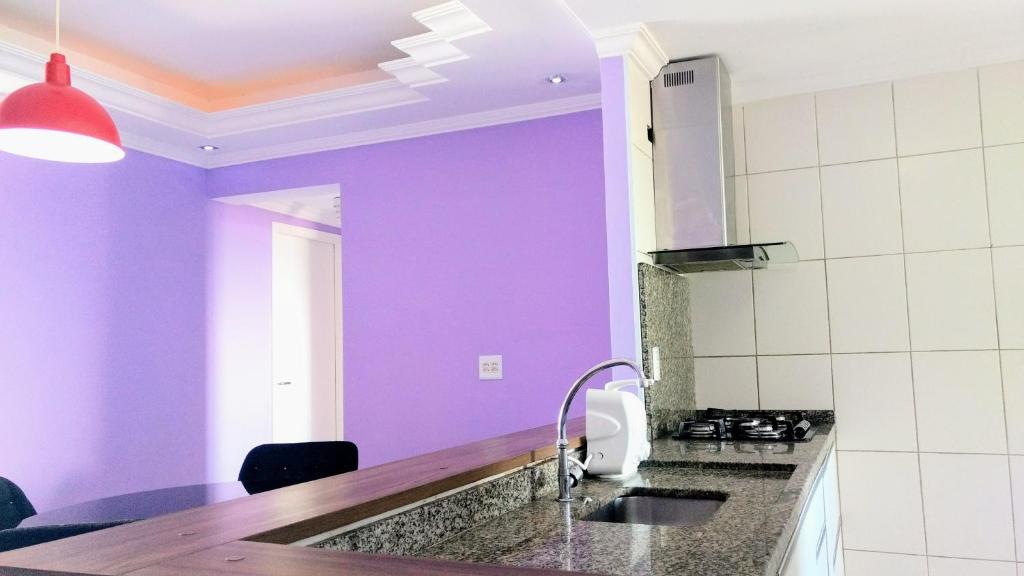 uma cozinha com paredes roxas e um lavatório em Apartamento para relaxar de frente a praia na Praia Grande