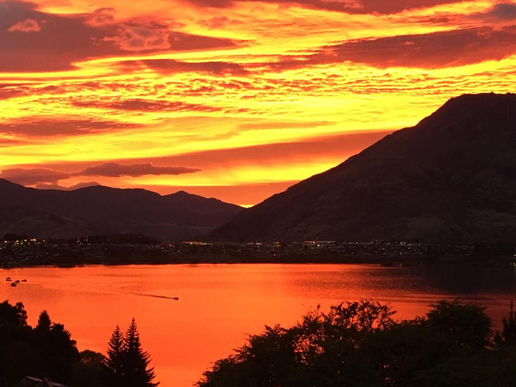 a sunset over a lake with mountains in the background at Breakfast at Tiffanys in Queenstown