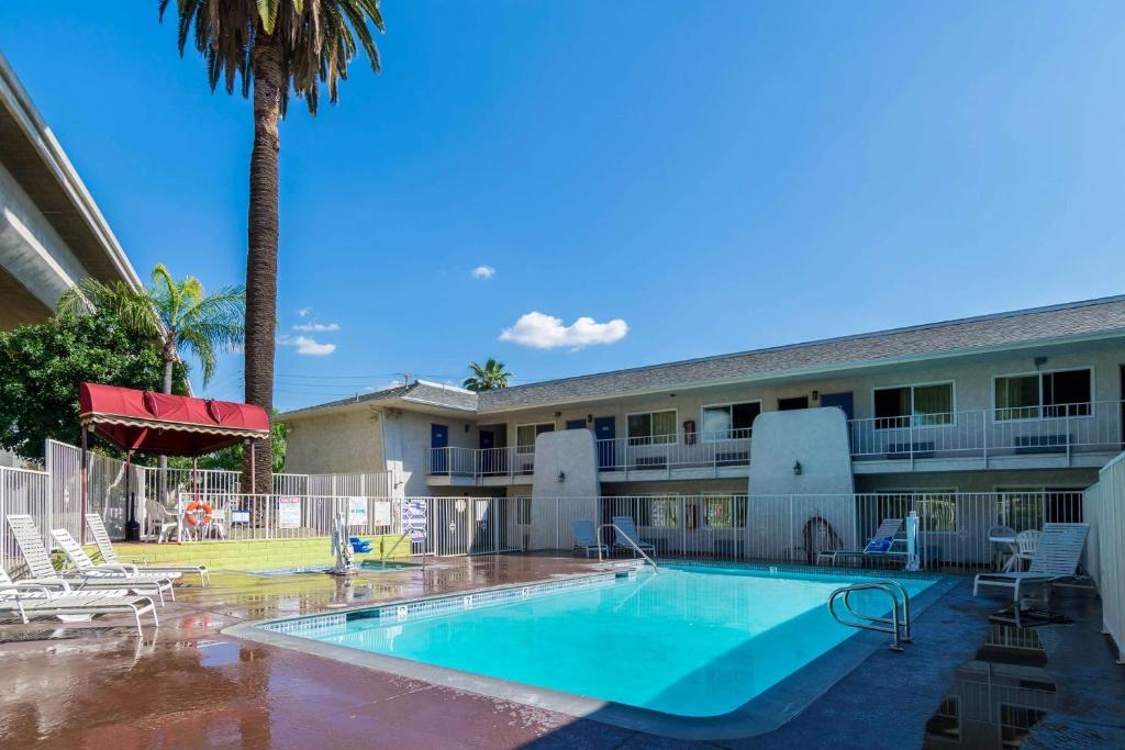 a pool in front of a hotel with a palm tree at Motel 6-Redlands, CA in Redlands