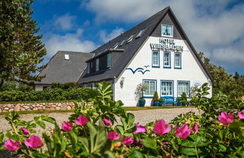 une maison avec des fleurs devant elle dans l'établissement Hotel Wiesbaden, à Wenningstedt