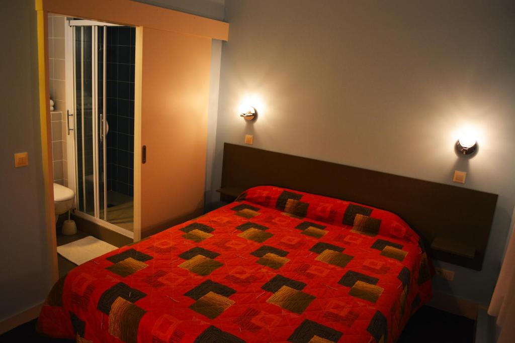 a bedroom with a bed with a red comforter and a window at Hôtel Le Lyon Bron in Bron