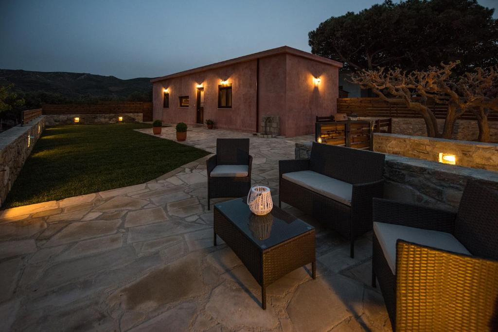 un patio con sillas y mesas y un edificio en Lardas Luxury Country House en Kissamos