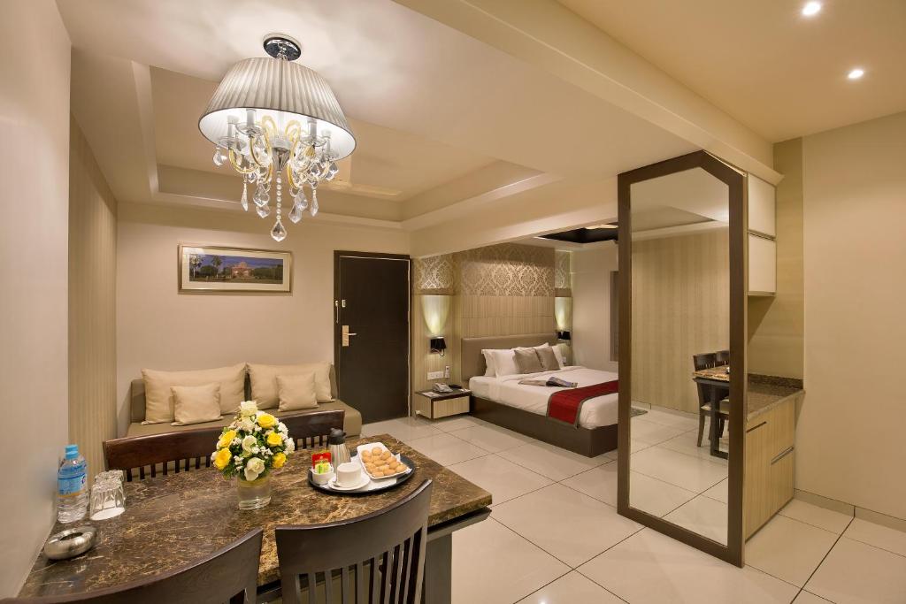 a hotel room with a bed and a dining room at The Baroda Residency in Vadodara