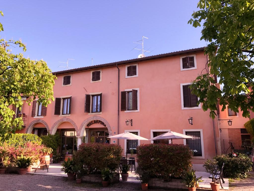 ein rosafarbenes Gebäude mit Sonnenschirmen davor in der Unterkunft Corte Malaspina in Castelnuovo del Garda