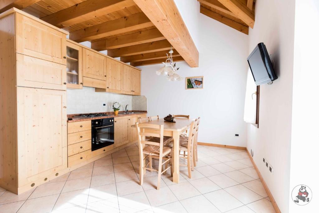 una cucina con armadi in legno e tavolo con sedie di RESIDENCE-HOTEL CIMBRO a Mezzaselva