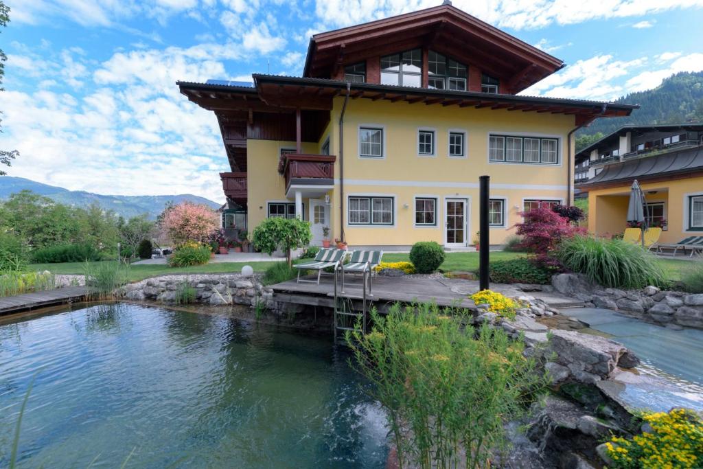 ein Haus mit einem Teich davor in der Unterkunft Haus am Hammerrain in Flachau